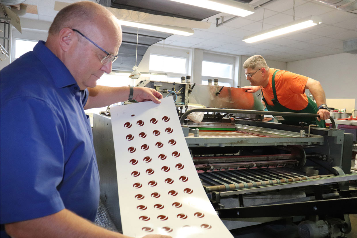 Mitarbeiter prüfen bedruckte Bogen an der Maschine